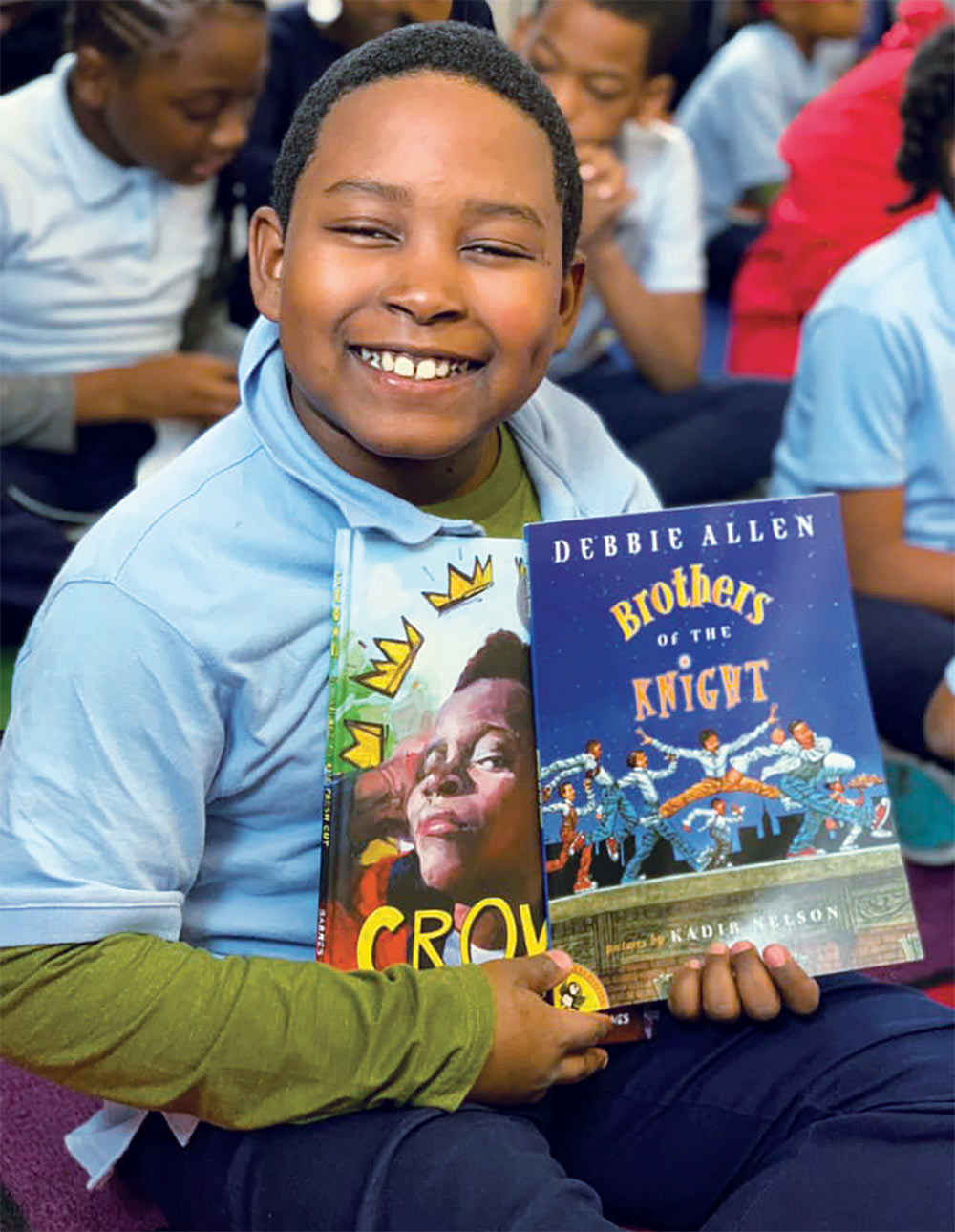 Young boy smiling while holding up books