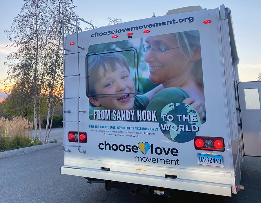 decal of woman holding child on back of Choose Love tour bus