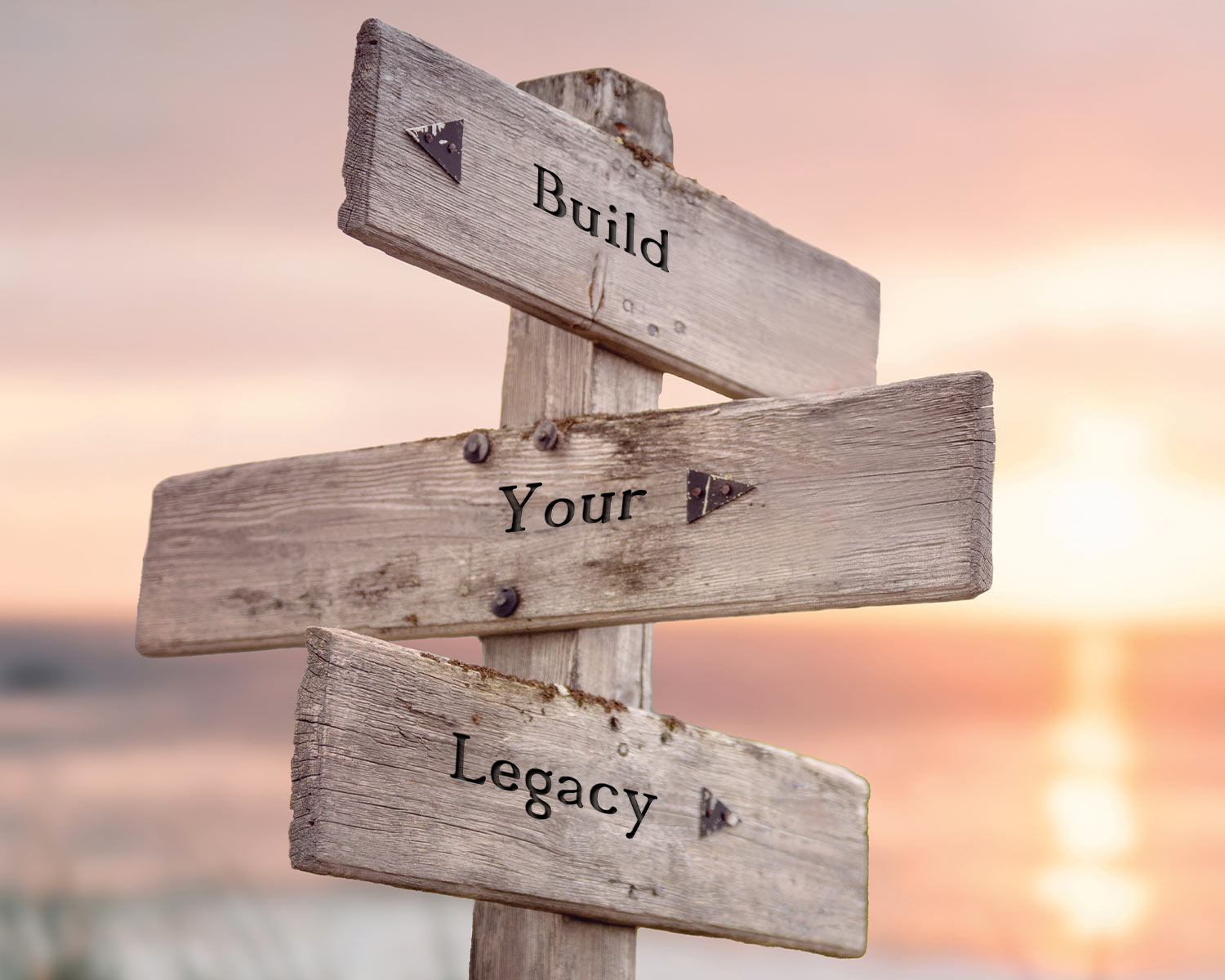 a wooden directional sign with three board reading "Build", "Your", and "Legacy"